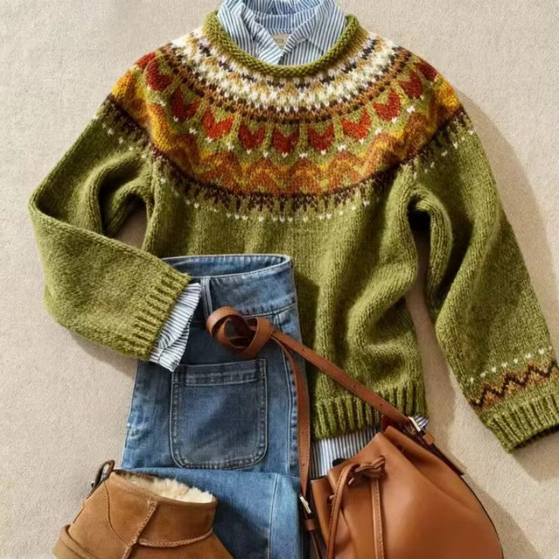 Flat lay of a green knit sweater with a multi-colored patterned yoke, paired with blue jeans, brown boots, and a matching bag.