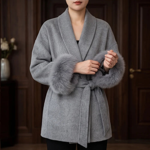 Woman wearing a luxurious gray wool wrap coat with wide lapels and thick gray faux fur cuffs, tied at the waist.